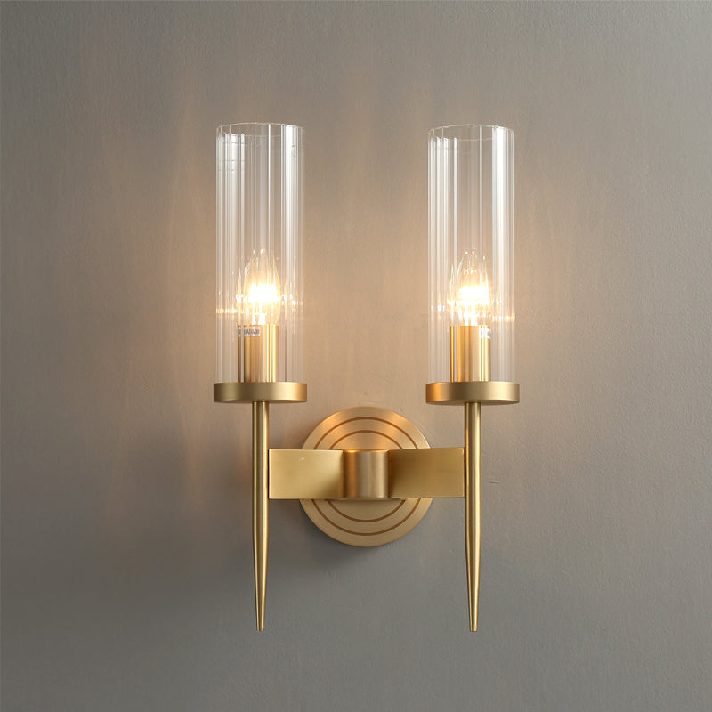 A minimalist interior features an American style copper wall lamp with an elegant lighting effect, dual-bulb E14 LED bulbs, and glass covers. A large green plant is placed on the left, complementing a simple bedroom with a curved entryway and nighttime ambiance in the background.