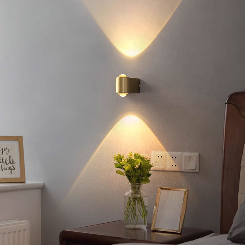 The Linear brass wall light, featuring Osram Chip technology, offers a minimalist design with warm yellow lights and three horizontal fixtures, casting soft patterns on a gray wall. Its sleek modern aesthetic and 3500K color temperature blend style and functionality harmoniously.