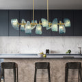 Modern kitchen with a marble backsplash and a stylish chandelier featuring blue textured glass shades.