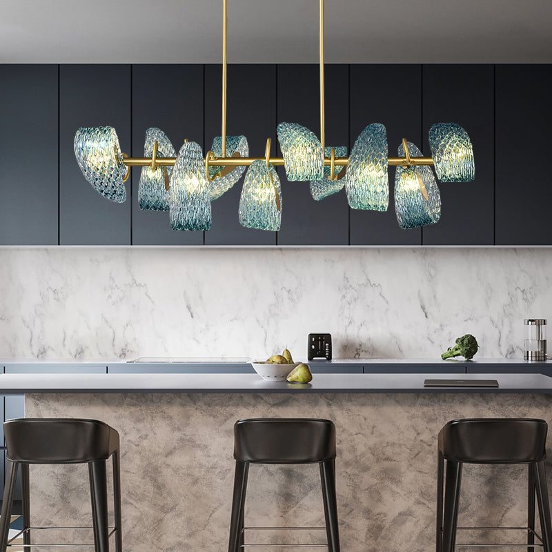 Modern kitchen with a marble backsplash and a stylish chandelier featuring blue textured glass shades.
