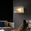 Textured glass wall sconce illuminating a modern living room with a sofa and chair.