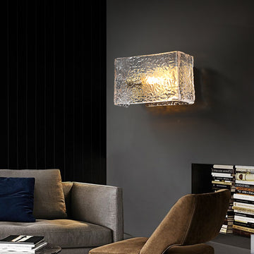 Textured glass wall sconce illuminating a modern living room with a sofa and chair.