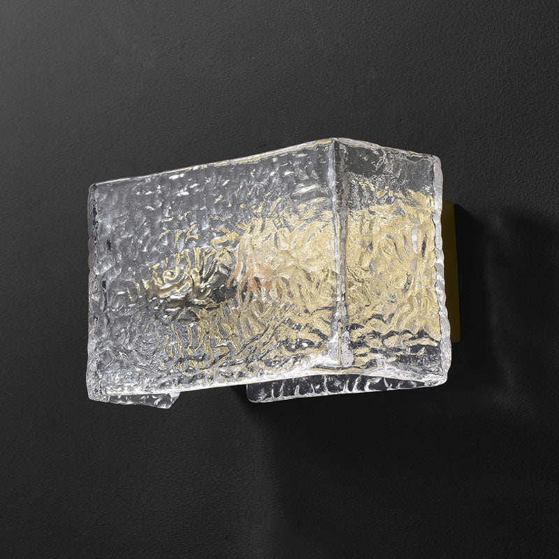 Textured glass wall sconce with a golden glow on a dark background.