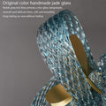 A glass sculpture featuring an elegant design topped with a striking gold ring, showcasing artistry and sophistication.