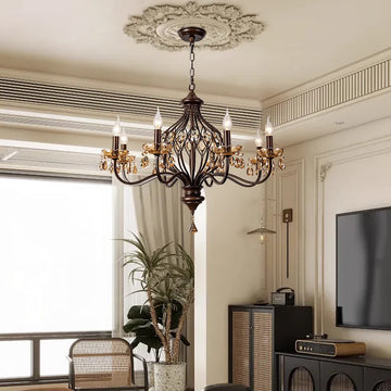 Elegant chandelier with candle-shaped lights in a chic room with decorative molding.