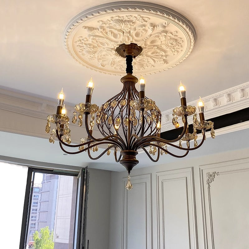 Elegant chandelier with candle-shaped lights in a chic room with decorative molding.