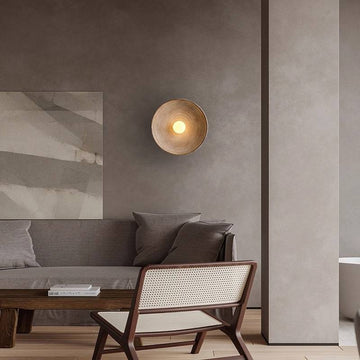 A modern living room showcases a gray sofa, abstract art, and a woven chair. The Japanese Retro Wall Lamp with an LED G4 bulb casts warmth, enhancing the neutral tones and minimalist decor that create a sleek Wabi-Sabi style ambiance.