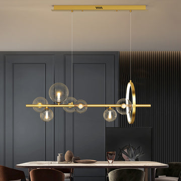 Modern chandelier above a dining table in a room with dark paneled walls and decor items.