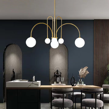 In a modern dining room, the St Kilda Chandelier with five globe lights hangs over a table adorned with two black vases. Dark walls, arched niches, and tall wood paneling accentuate the rooms elegance.