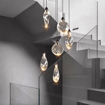 Modern pendant lights over stairwell with grey monochromatic palette.
