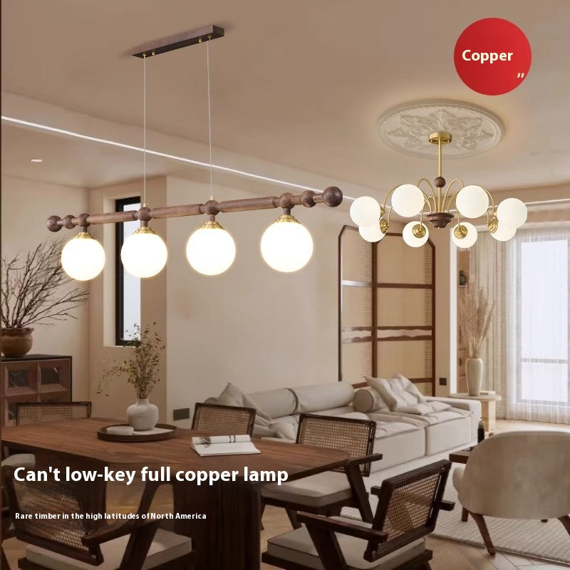 A wooden horizontal bar with four spherical pendant lights hanging over a table, with a "Copper" label in the background.
