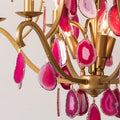 An exquisite chandelier featuring pink stones, gracefully hanging and casting a warm glow in the surrounding area.