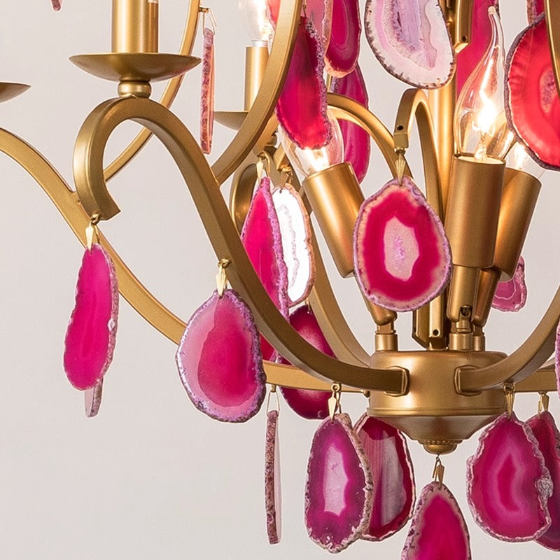 An exquisite chandelier featuring pink stones, gracefully hanging and casting a warm glow in the surrounding area.