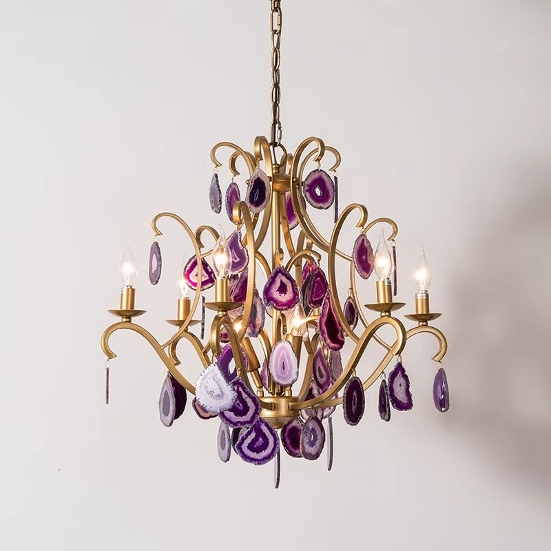 A luxurious chandelier adorned with purple and gold stones, elegantly suspended from the ceiling, illuminating the space.