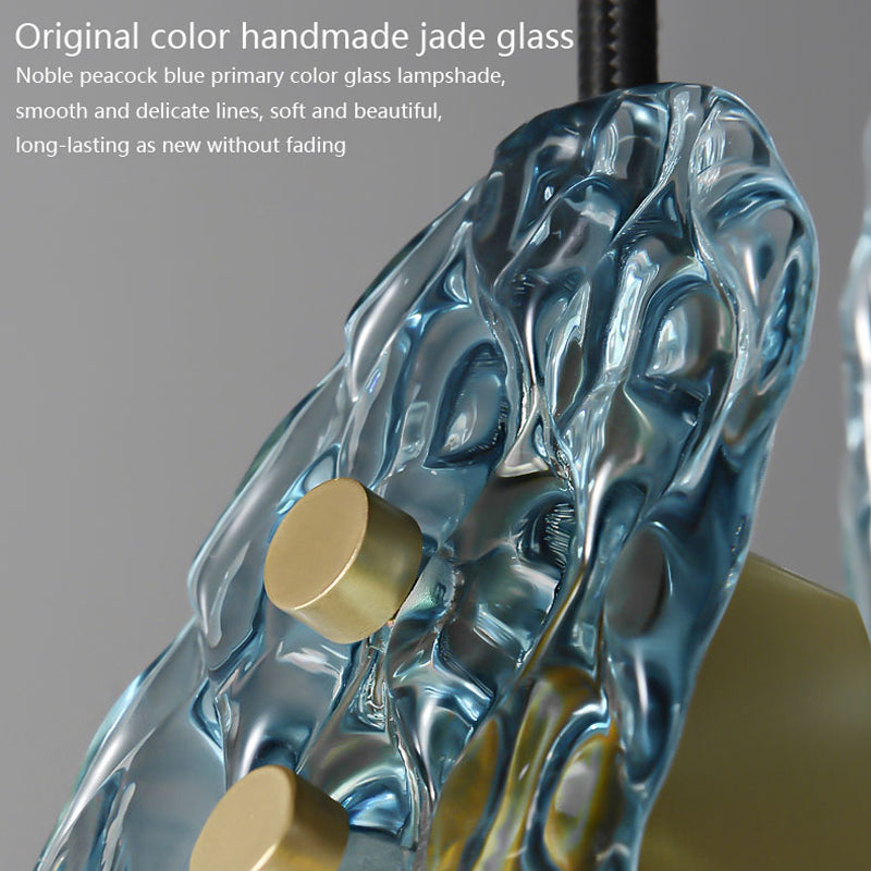 Close-up of a peacock blue textured glass lampshade with delicate patterns and brass fixtures.
