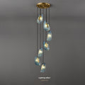 A modern chandelier with seven pendant lights in teardrop-shaped, textured glass shades, against a grey background.