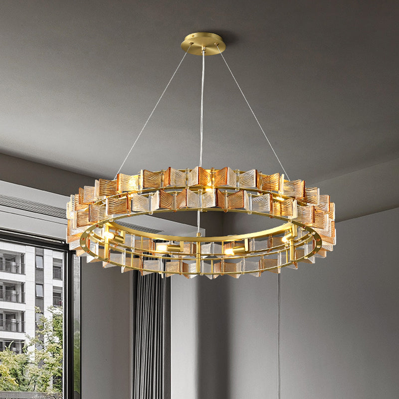 The Chandelier Series features a modern circular design with geometric gold and glass, enhancing contemporary lighting. Large windows and gray curtains frame an urban scene beyond. Its adjustable height offers versatile style in any space.