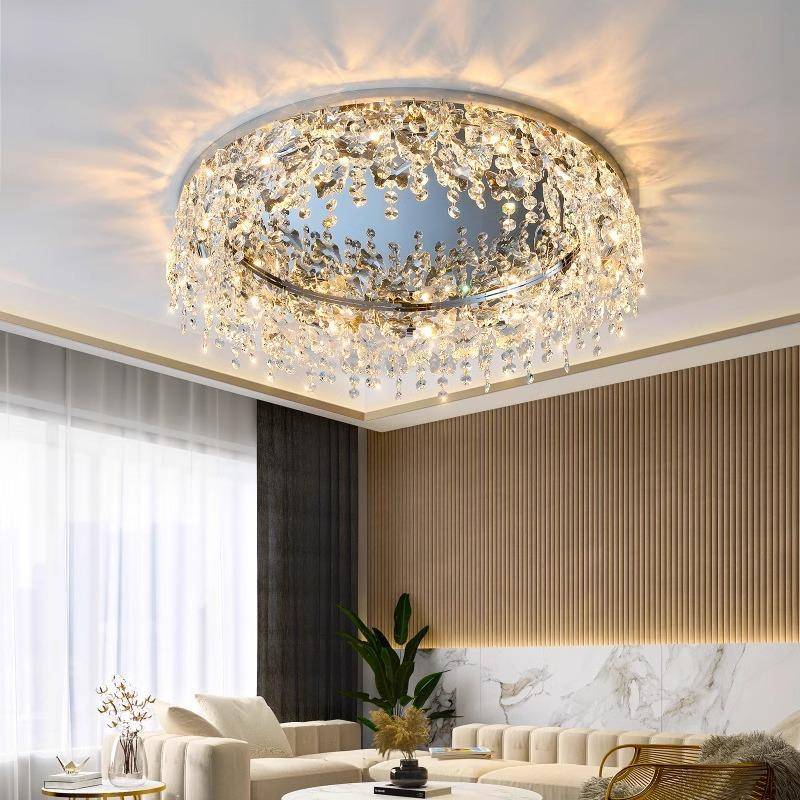 The luxurious living room features the Butterfly Crystal Ceiling Lamp with cascading droplets and an elegant LED glow. Its DALI dimming enhances the ambiance, perfectly complementing a plush sofa, marble accents, and large windows adorned with sheer curtains.