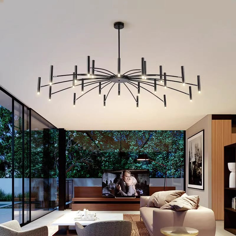 Modern living room with a starburst chandelier, stylish furnishings, and a large window overlooking greenery.