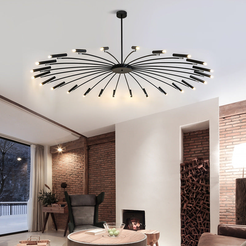 Modern chandelier with radiating arms and lights in a stylish room with a brick wall and fireplace.