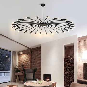 Modern chandelier with radiating arms and lights in a stylish room with a brick wall and fireplace.