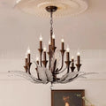 Elegant chandelier with ten candle-shaped bulbs, ornate metal arms, and leaf-like decorations hanging from a ceiling with a decorative medallion.