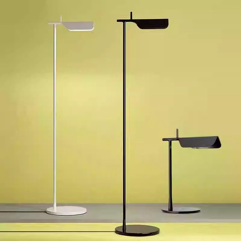 Three Simple floor lamps stand against a yellow-green gradient backdrop. Available in black, white, and dark gray, they feature flat rectangular light heads with G9 LED bulbs and circular bases. Their minimalist design emphasizes clean lines for a modern touch.