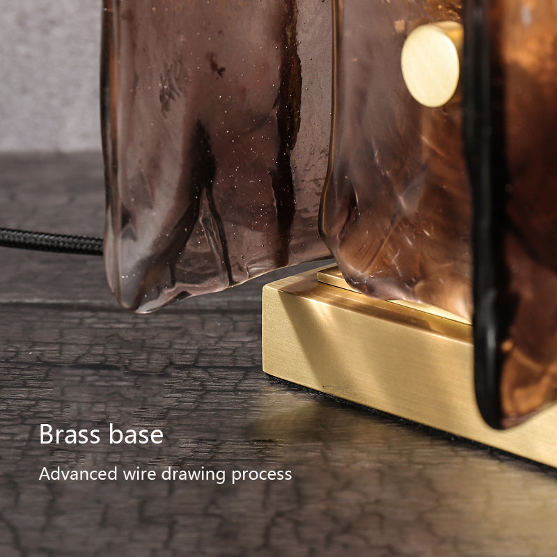 Close-up of the Vintage Brass Glass Table Lamp showcasing a polished brass base and textured hand-blown amber glass shade. The text highlights Brass base and Advanced wire drawing process, merging elegance with energy-efficient lighting in its wavy glass design.