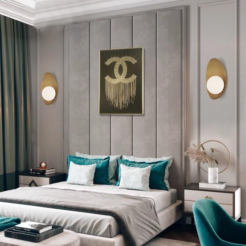 A modern bedroom showcases a large bed with teal and light gray pillows, flanked by two Metal Boat-Shaped Wall Lights and centered by fringe art. Teal curtains and a matching chair bring color against neutral walls and furniture for a sleek appearance.