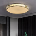 Modern golden ceiling light fixture in a room with dark curtains and part of a green statue visible.
