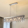 A modern Crystal Butterfly Chandelier graces the ceiling, adorned with K9 crystals and multiple lit bulbs, casting a warm glow. The beige ceiling complements its shimmering elegance while gray curtains are partially visible in the background.