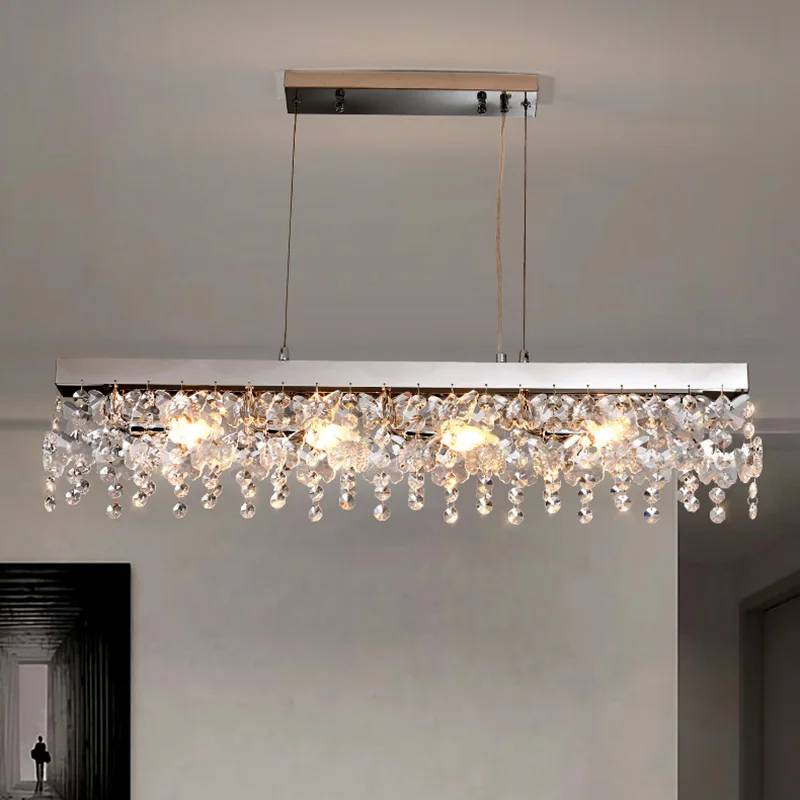 The Crystal Butterfly Chandelier exudes luxury with cascading K9 crystals and glowing bulbs, suspended by wires from a ceiling mount. The minimalist interior features a dark doorway on the left.