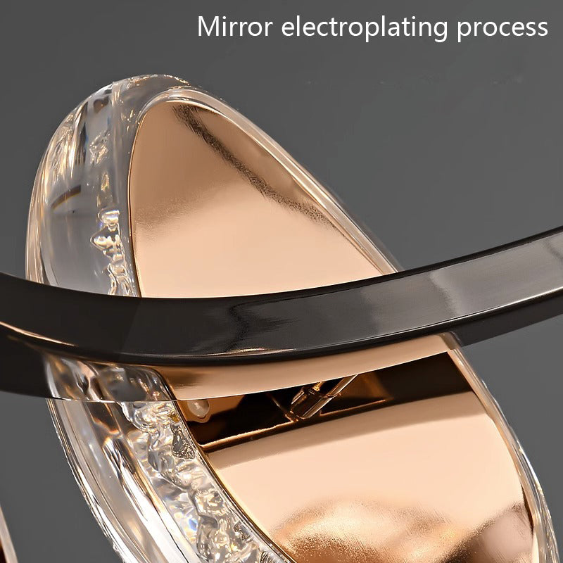 A close-up of a round chandelier featuring a metallic and transparent design with a reflective surface, black band, and shiny copper-like finish showcasing the mirror electroplating process.