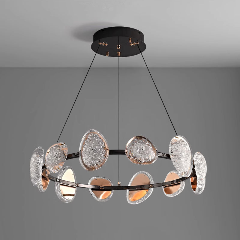 The sleek round chandelier features a black metal frame adorned with textured, translucent oval glass disks and a smart dimming function. Suspended by three thin cables, it enhances any spaces lighting with modern style against a plain gray background.