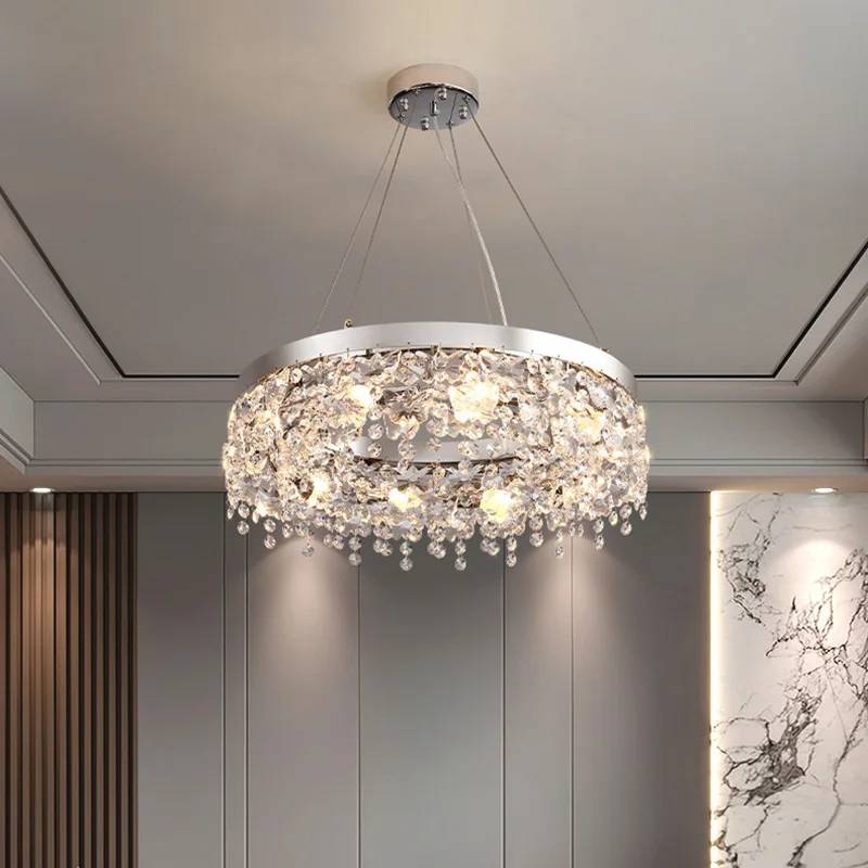 A Crystal Butterfly Chandelier with circular metal frame and cascading K9 crystals, complemented by adjustable recessed ceiling lighting, enhances the rooms refined elegance with marble and wooden panel wall details.