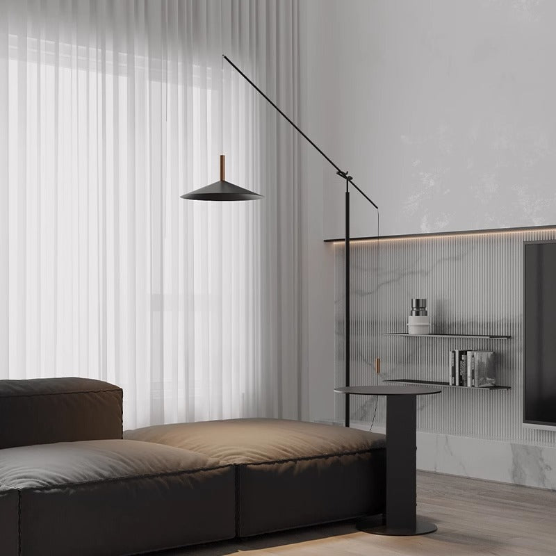 A minimalist living room showcases a dark brown sectional sofa and the sleek Velluto Floor Lamp. Sheer white curtains and a modern side table add charm, while light gray walls with built-in shelves and adjustable lighting enhance the contemporary design.