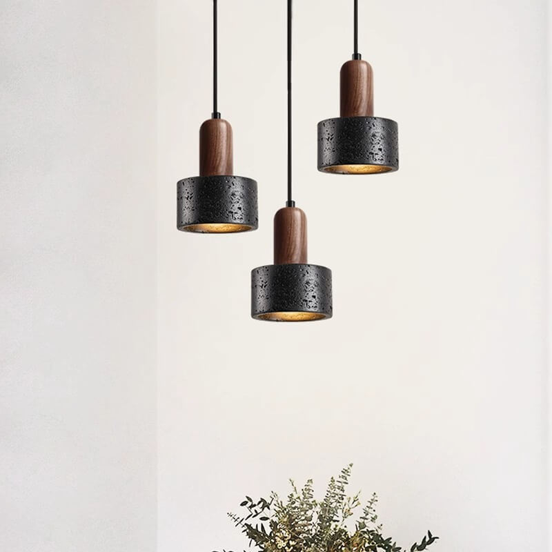 Three Vintage Yellow Travertine Chandeliers with black cylindrical shades and wooden tops, featuring adjustable E27 LED bulbs, elegantly hang from the ceiling against a white background. A small bouquet of greenery and white flowers adds freshness at the bottom.