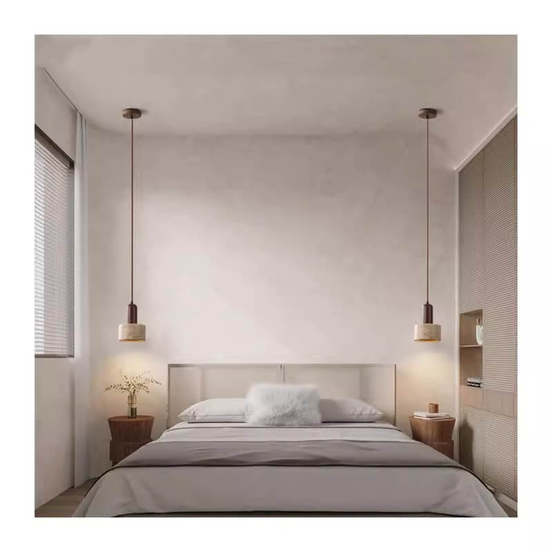 A minimalist bedroom showcases a bed centered against a plain wall, with two wooden side tables on either side. Above each table, a Vintage Yellow Travertine Chandelier hangs. A vase with plants sits on the left table, and neutral tones along with soft lighting create a serene atmosphere.