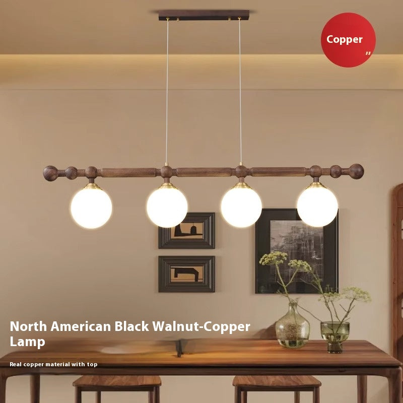 A wooden horizontal bar with four spherical pendant lights hanging over a table, with a "Copper" label in the background.