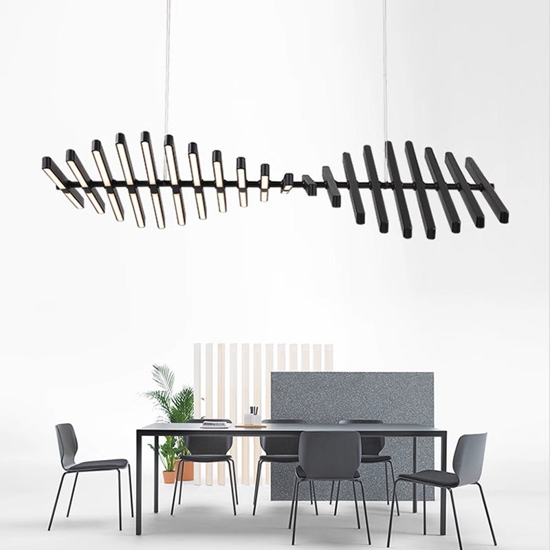 A modern dining room features the Fishbone Wave Chandelier, a sleek, black pendant light with adjustable illumination. A rectangular table is surrounded by six gray chairs, while minimalist decor like a small potted plant enhances the white wall backdrop, creating an elegant and customizable setting.