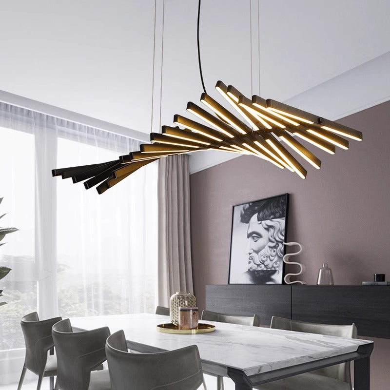 A modern dining room showcases the artistic Fishbone Wave Chandelier with adjustable lighting, casting a warm glow from horizontal rods. Below, a white table sits among gray chairs, while a monochrome portrait adorns the taupe wall. Sheer curtains elegantly drape over large windows.