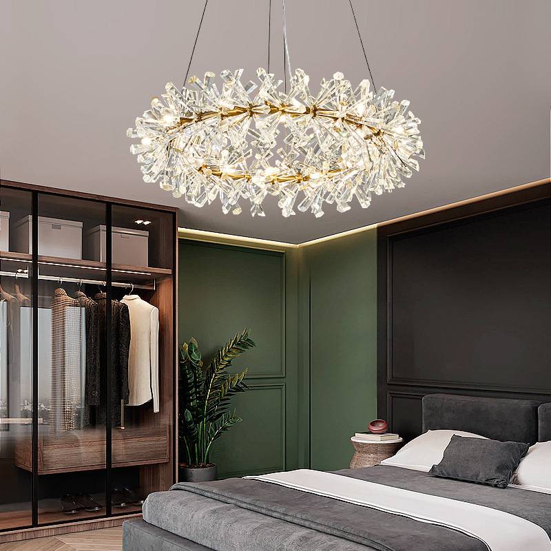 A modern bedroom showcases a sleek Crystal Branch Chandelier with adjustable wire. It includes a plush bed with grey bedding, a glass wardrobe for clothes, and a potted plant on a dark green wall. G4 LED bulbs provide energy-efficient soft lighting for a cozy atmosphere.