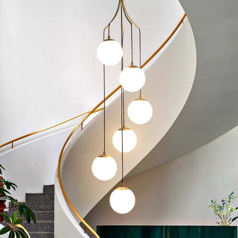 A contemporary staircase featuring a luxurious gold and white chandelier overhead, enhancing the elegant ambiance.
