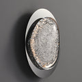 The wall lamps circular design, with textured glass like ice, complements an energy-efficient LED light creating an elegant look. It is ideally suited for bedroom use and mounts seamlessly on a smooth dark gray wall.